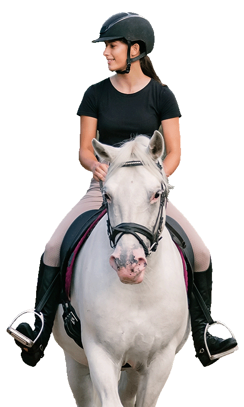 A smiling young rider in a black helmet and t-shirt sits atop a white horse, looking to the side while riding in an upright, relaxed posture.